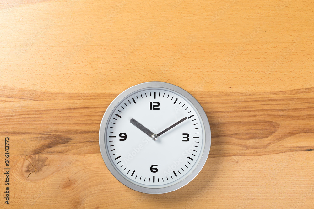 White wall clock with a yellow used hanging on the wall. Minimalist image of a wall clock on a wooden background with copy space White wall clock with a yellow used hanging on the wall. Minimalist image of a wall clock on a wooden background with copy space