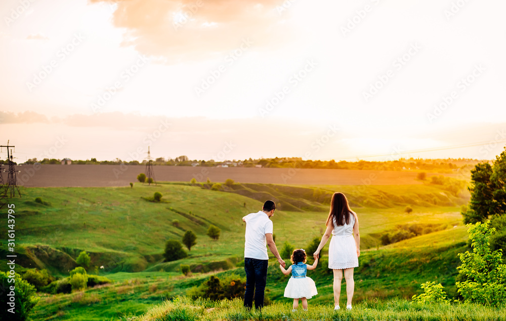 Four human, girl, young woman and man, Group of people, family watching over the sunset. Mountains, green hills. Nature and travel background