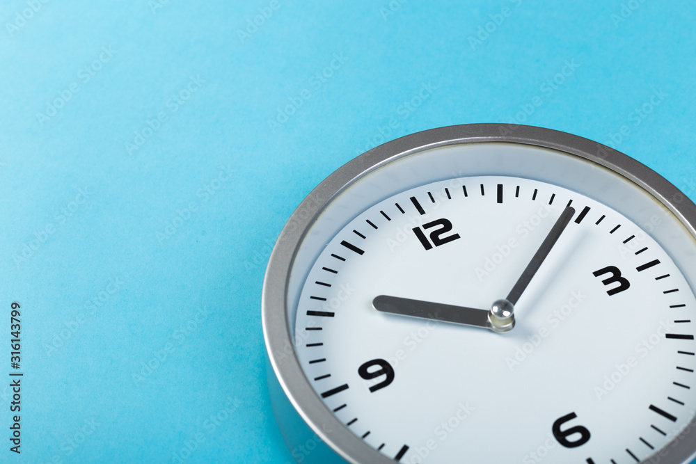 White wall clock with a yellow used hanging on the wall. Minimalist image of a wall clock on a blue background with copy space White wall clock with a yellow used hanging on the wall. Minimalist image of a wall clock on a blue background with copy space