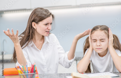Teen girl covers her ears and closed eyes while her mother scolds her for poor study. Family relationships