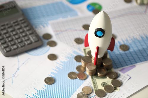 Small toy rocket, coins, calculator and official documents at business desk, selective focus. Business process, profit, earning, financial analysis concept © H_Ko