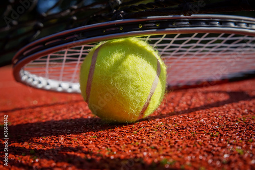 Detail of tennis rocket over ball on court surface