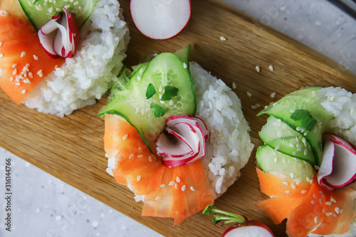 Trendy Asian food – sushi donuts with fresh vegetables. Contemporary snack for vegans and vegetarians. Rice, carrots, cucumber and radish in bagel shape, close up