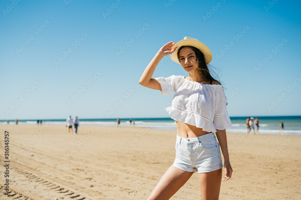 girl on a wide sandy beach poses for a photographer