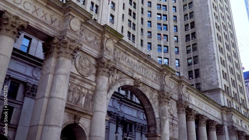 Low angle shot of the Manhattan Municipal Building - famous New York Landmark, in contrast with modern skyscrapers behind it that come into the frame later
