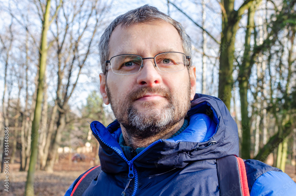 Portrait of a middle-aged man in down jacket in the barren forest Portrait of a middle-aged man in down jacket in the barren forest
