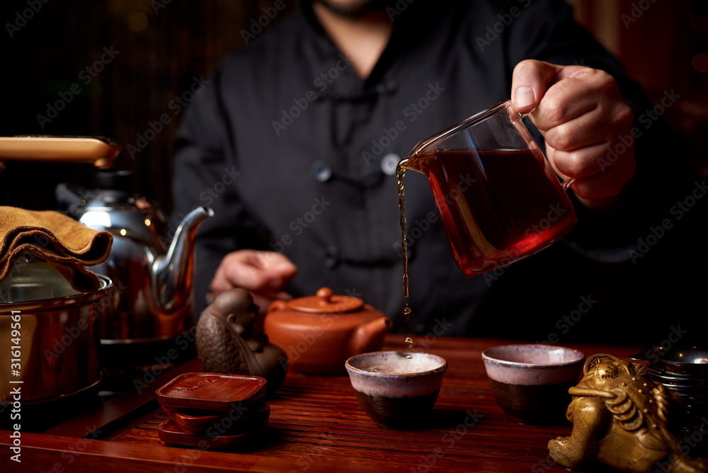 Tea ceremony. A young man pours tea from a teapot.