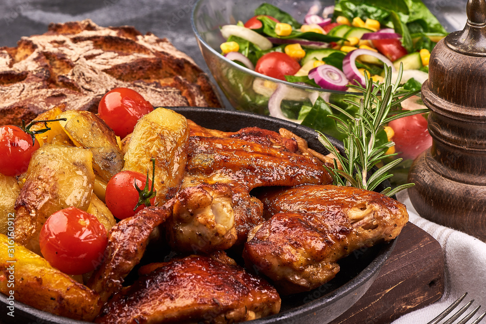 Fototapeta premium Delicious Roasted chicken wings with baked potatoes on rustic background