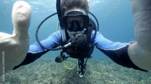 Underwater selfie photo of a male suba diver in the blue ocean.