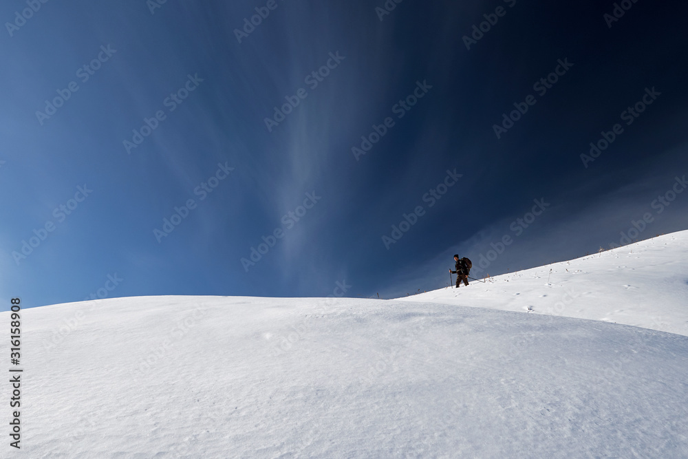 Hiker is walking on the winter trail against blue sky background. minimalist style