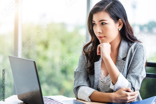 Happy attractive Asian business woman working with a laptop and financial document at office, successful action, Business concept.