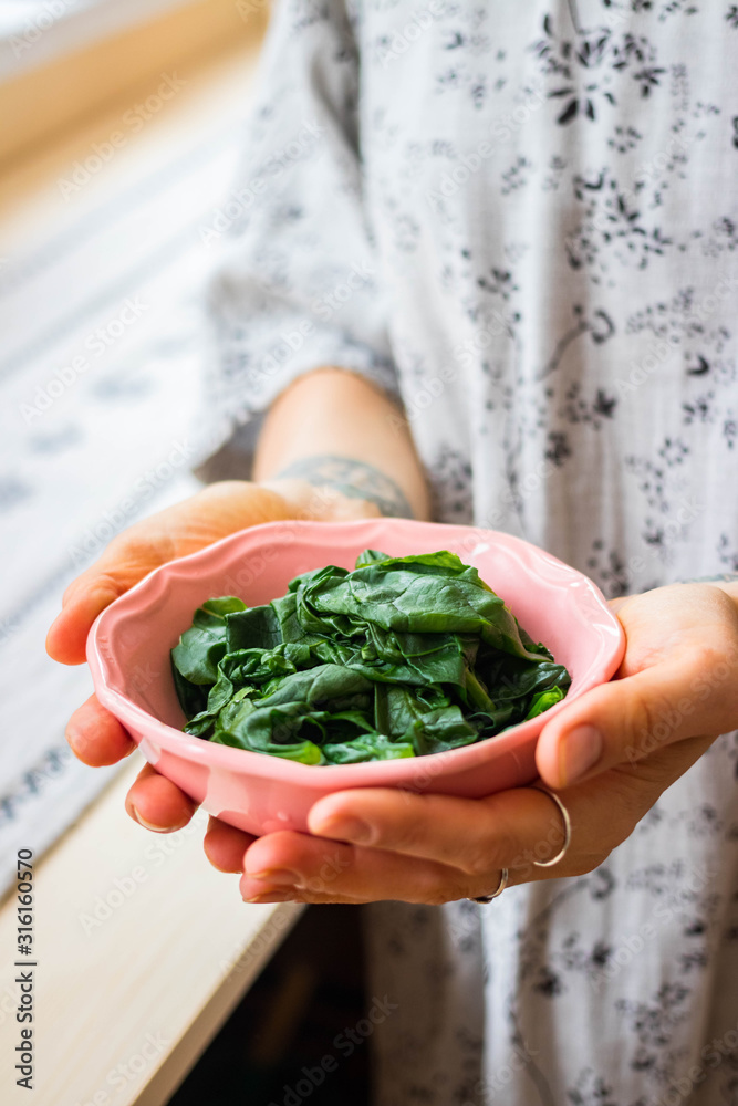 Φωτογραφία Sauteed spinach leaves. Woman holds in hands. Vegan healthy food