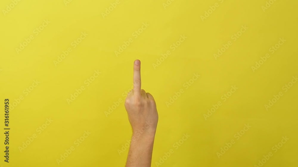Male hand on a yellow background shows a middle finger Male hand on a yellow background shows a middle finger