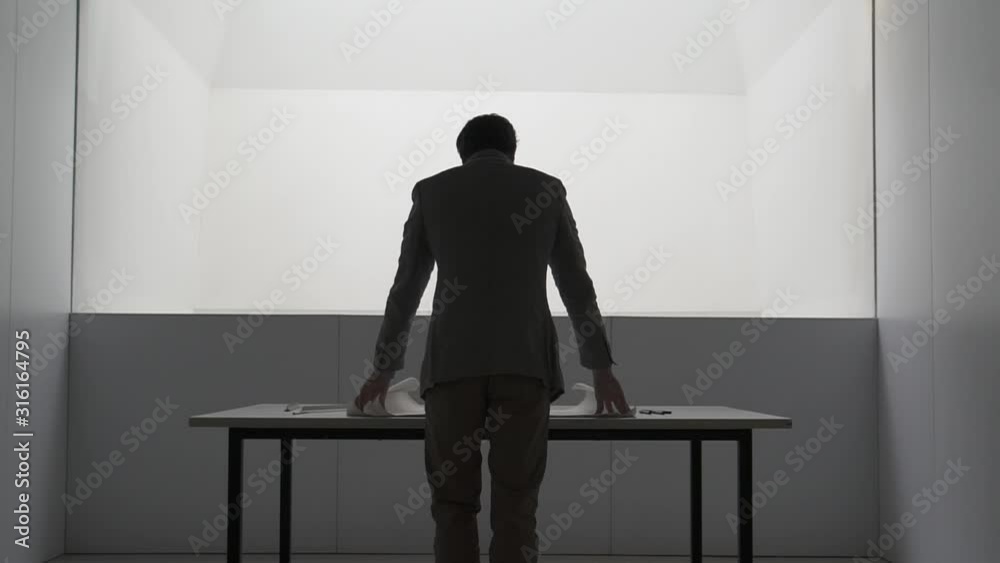 Hombre arquitecto abre planos de construcción sobre mesa HD