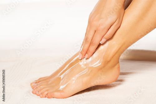 a young woman applies lotion to her feet © vladimirfloyd