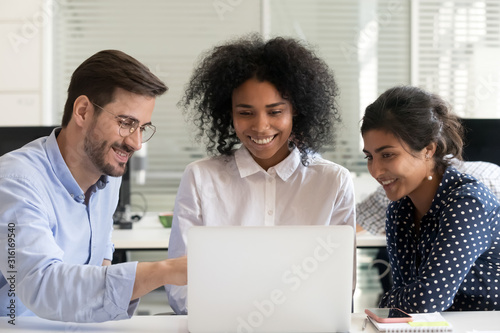 Multiracial happy colleagues talk working together on laptop