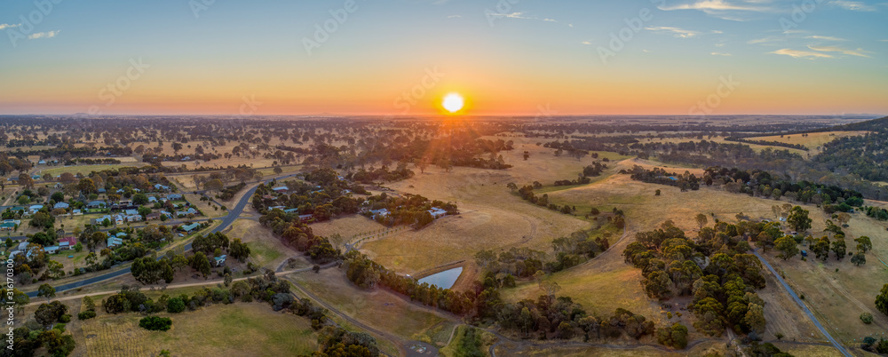 Sun touching the horizon at sunset over Australian outback - wide aerial panorama