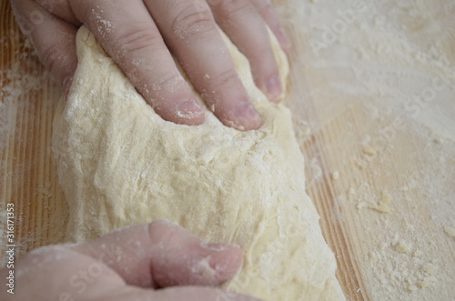 cook kneads pizza dough with his hands
