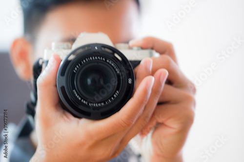 A blurry photo of man looking into the camera's viewfinder and taking photo.