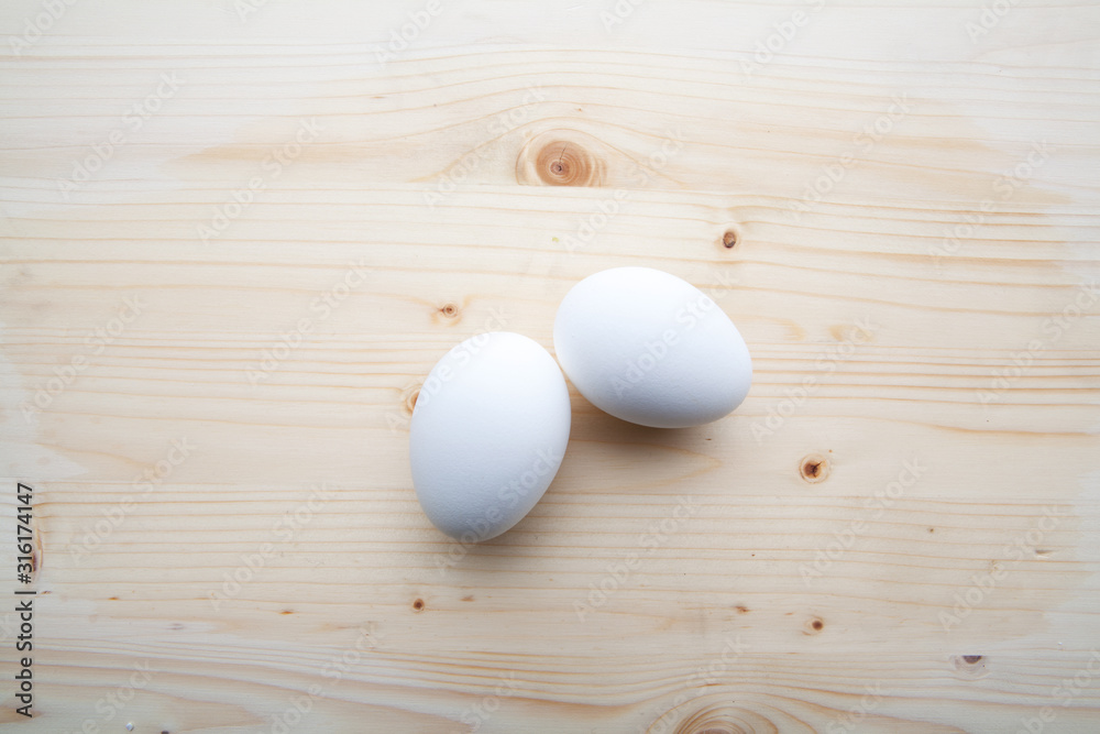 Two white egs on a wooden background.