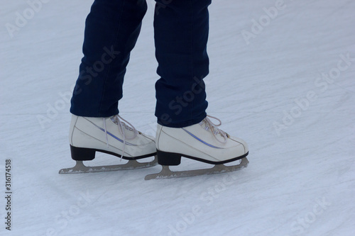 Closeup female legs with ice skates. Winter outdoor activity.