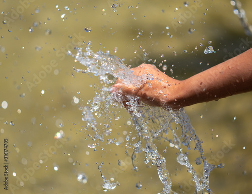 Hand of a girl in the spray of water of the fountain