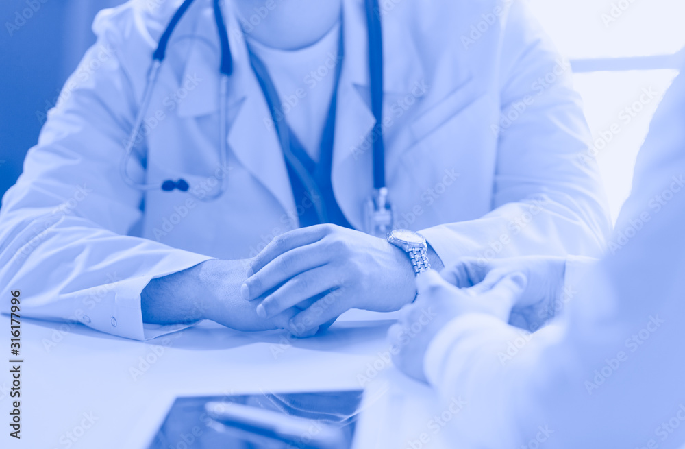 Portrait of a male doctor with laptop sitting at desk in medical office Portrait of a male doctor with laptop sitting at desk in medical office