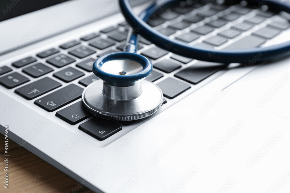 Laptop and stethoscope on table, closeup. Concept of technical support Laptop and stethoscope on table, closeup. Concept of technical support
