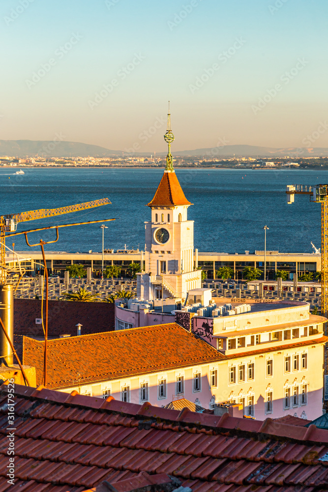 Lisbon harbor tower at sunset with a crane and a view on the tagus river