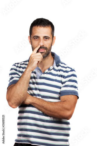 uomo con maglietta a righe su sfondo bianco, si tocca il naso con un dito
