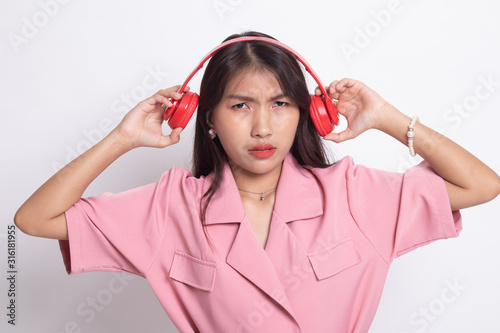 Too loud.  portrait of  young asian woman  holding  headphones and making unhappy face.