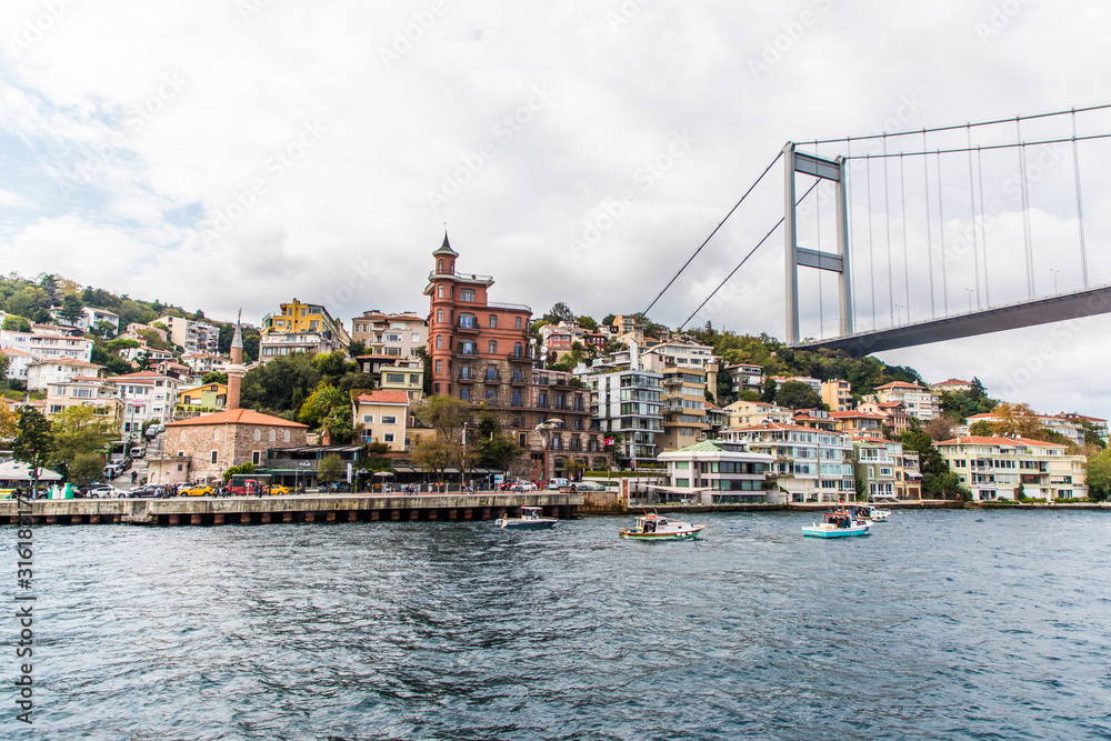 Fototapeta premium Tourist ship sails on the Golden Horn, Istanbul, Turkey. Scenic sunny panorama of Istanbul city in summer. Beautiful waterfront of Istanbul at sunset. Concept of traveling and vacation in Istanbul.