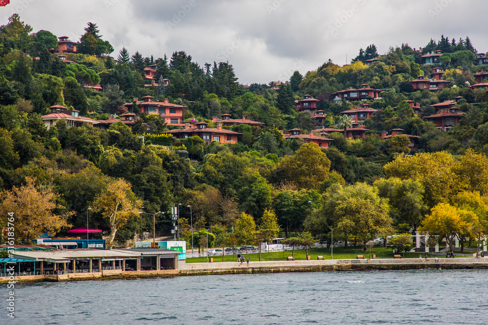 Tourist ship sails on the Golden Horn, Istanbul, Turkey. Scenic sunny panorama of Istanbul city in summer. Beautiful waterfront of Istanbul at sunset. Concept of traveling and vacation in Istanbul.