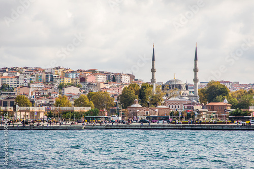 Tourist ship sails on the Golden Horn, Istanbul, Turkey. Scenic sunny panorama of Istanbul city in summer. Beautiful waterfront of Istanbul at sunset. Concept of traveling and vacation in Istanbul.
