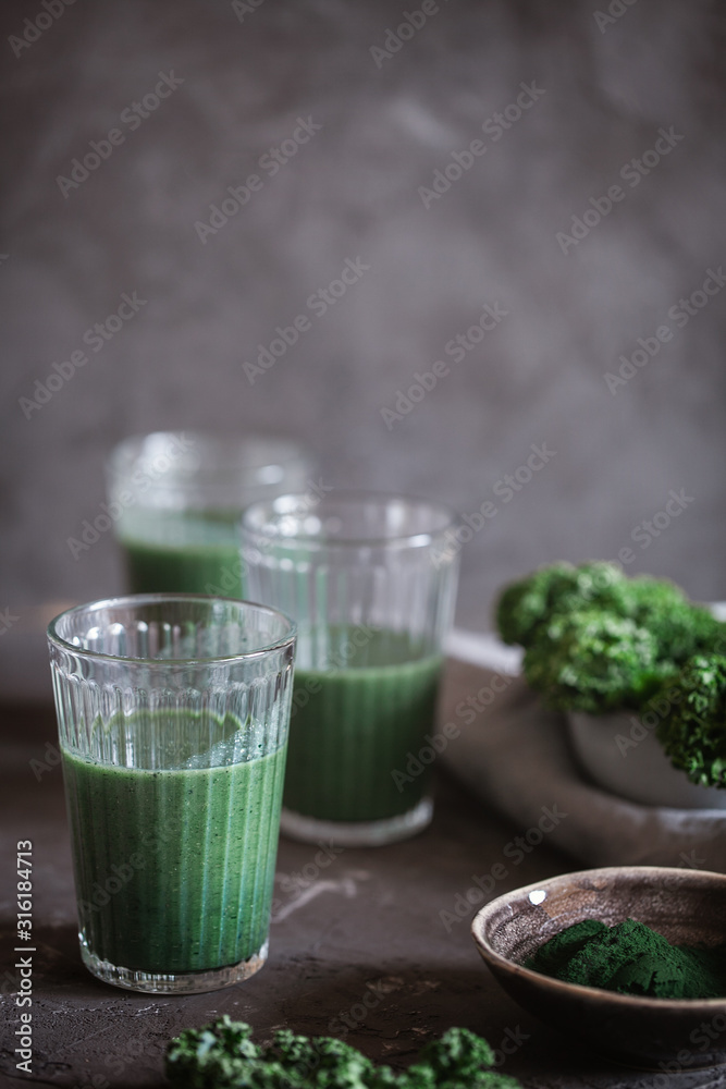 A healthy vegan drink green kale smoothie with spirulina for detox on dark background with copy space for text.Food and drink,dieting and nutrition concept.Vertical orientation