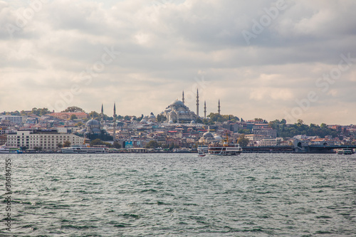 Tourist ship sails on the Golden Horn, Istanbul, Turkey. Scenic sunny panorama of Istanbul city in summer. Beautiful waterfront of Istanbul at sunset. Concept of traveling and vacation in Istanbul. © dianagrytsku