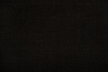 Close-up texture of natural weave cloth in dark and black color. Fabric texture of natural cotton or linen textile material. Seamless background.