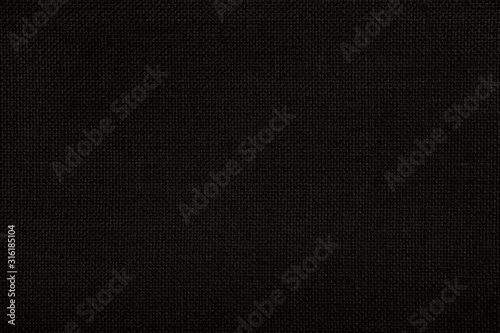 Close-up texture of natural weave cloth in dark and black color. Fabric texture of natural cotton or linen textile material. Seamless background.