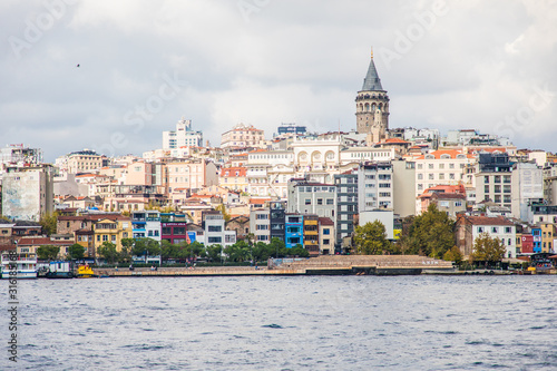 Tourist ship sails on the Golden Horn, Istanbul, Turkey. Scenic sunny panorama of Istanbul city in summer. Beautiful waterfront of Istanbul at sunset. Concept of traveling and vacation in Istanbul.