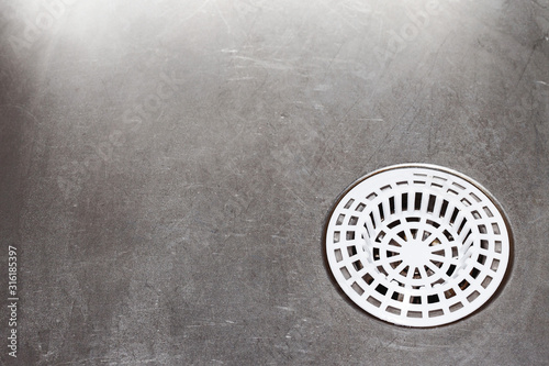 Metal kitchen sink. Plastic white sieve background.