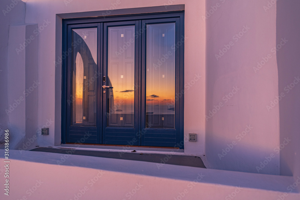 Fototapeta premium Tramonto riflesso sulla vetrata, isola di Santorini GR