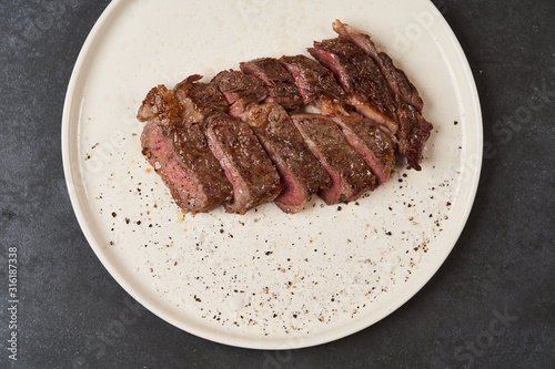 Grilled beef steak with spices on a white tray, close-up