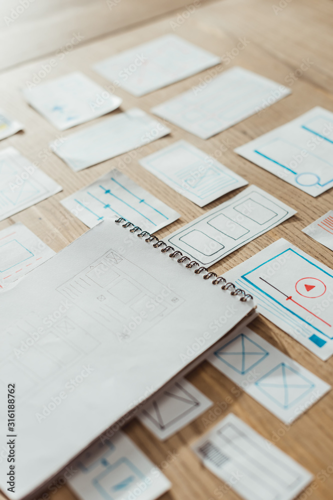 Fototapeta premium High angle view of notebook and user experience design sketches on wooden table