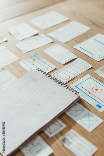 High angle view of notebook and user experience design sketches on wooden table