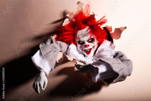 Fototapeta Naklejka Na Ścianę i Meble -  scary clown killer breaks through the wall. horror. Halloween concept.