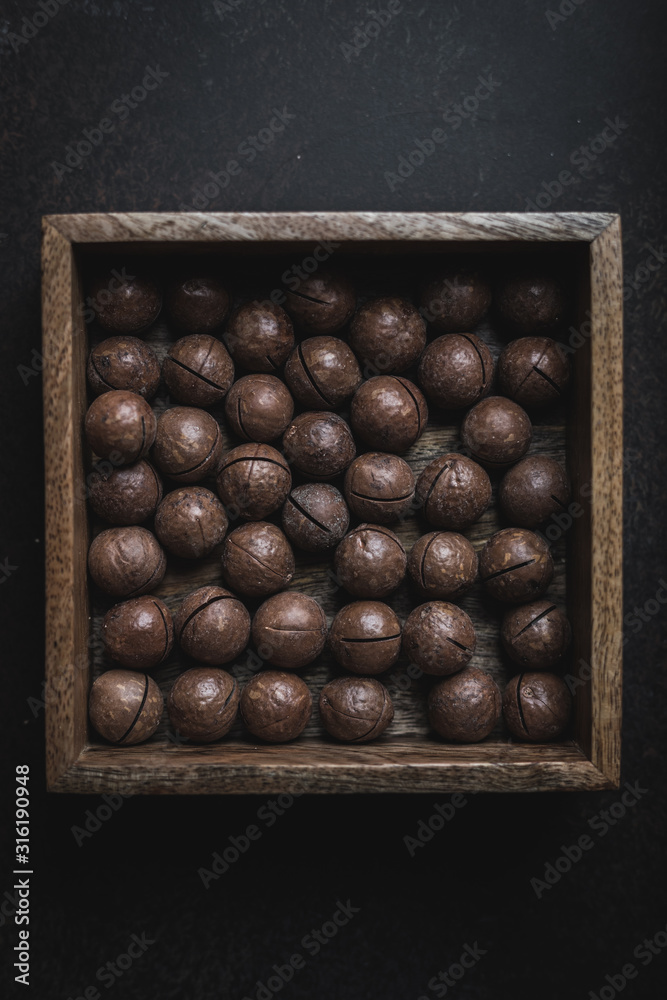 Inshell macadamia nuts in a wooden box pattern moody food photography Inshell macadamia nuts in a wooden box pattern moody food photography