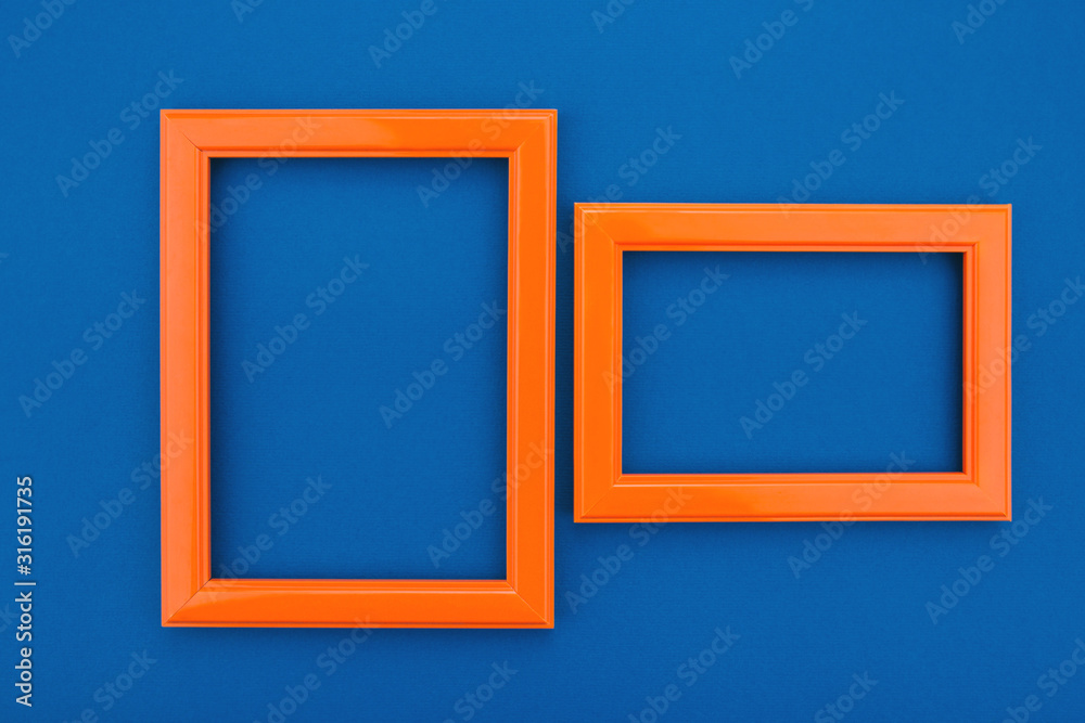 Empty orange frame on the classic blue background. Trendy greeting card. Minimal concept. Copy space for your text. Flat lay style. Top view. Empty orange frame on the classic blue background. Trendy greeting card. Minimal concept. Copy space for your text. Flat lay style. Top view.
