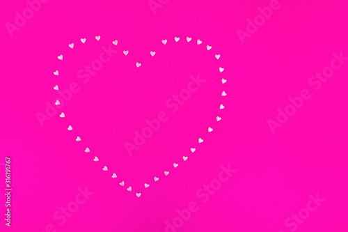 Bright pink background. Pink hearts on a pink background. Hearts sprinkles. Valentine day. Flat lay style. Top view. Place for design. Sweet background. Confetti.