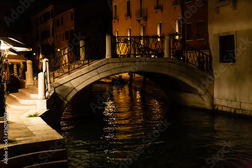 bridge above canal near ancient buildings at night in Venice, Italy