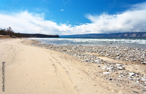 Lake Baikal in spring time. Sandy shore of Olkhon Island on the ice drift in the Small Sea Strait. Spring landscape  natural seasonal background